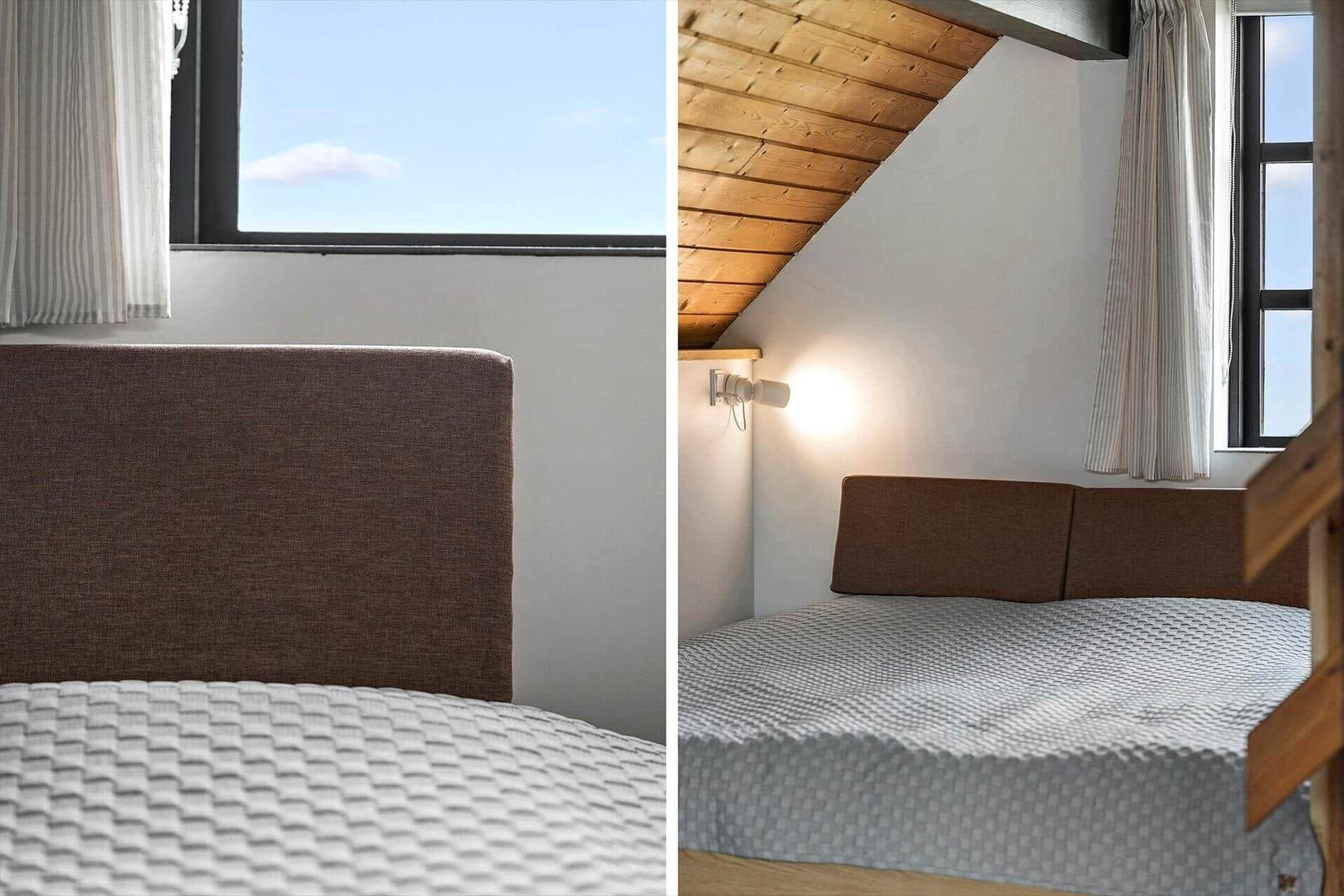Schlafzimmer mit Dachschrägen, Bett und Fenster mit Blick auf den Himmel.