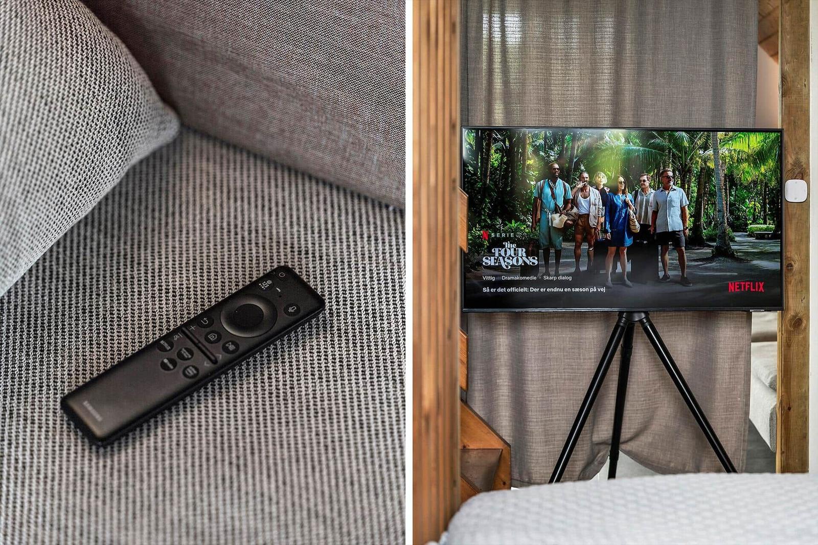 Fernseher auf Stativ zeigt Serie. Fernbedienung liegt auf Sofa.