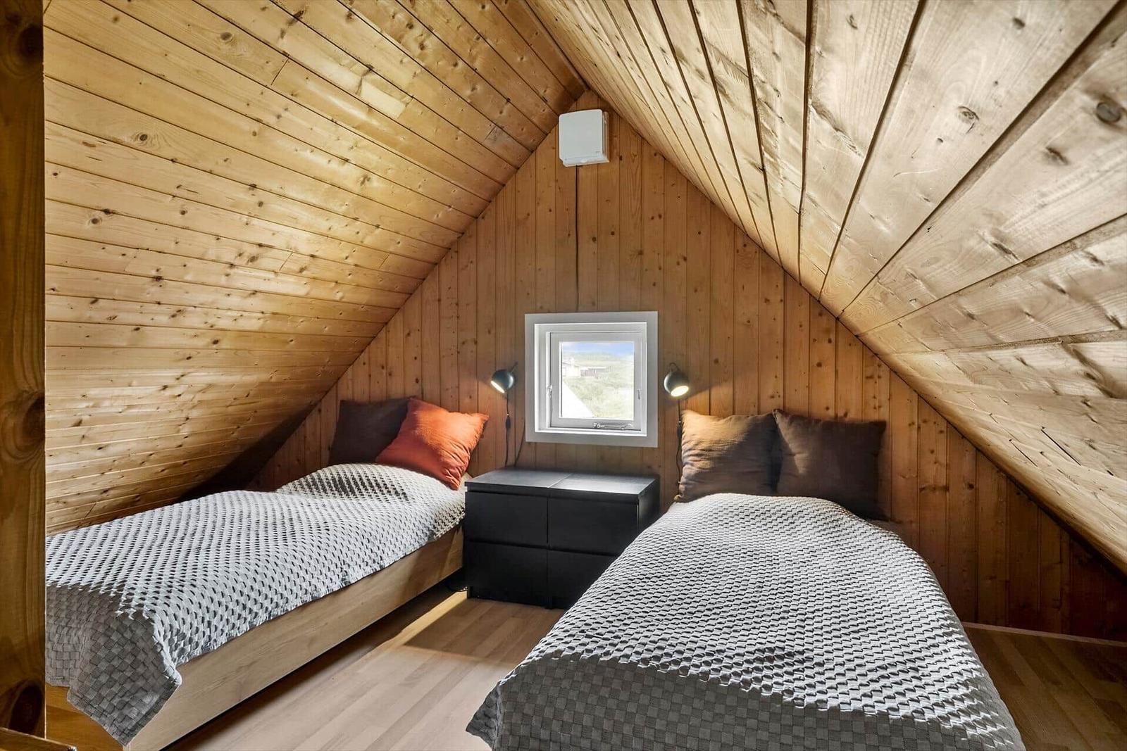 Zimmer mit zwei Betten, Holzwand und Dachfenster