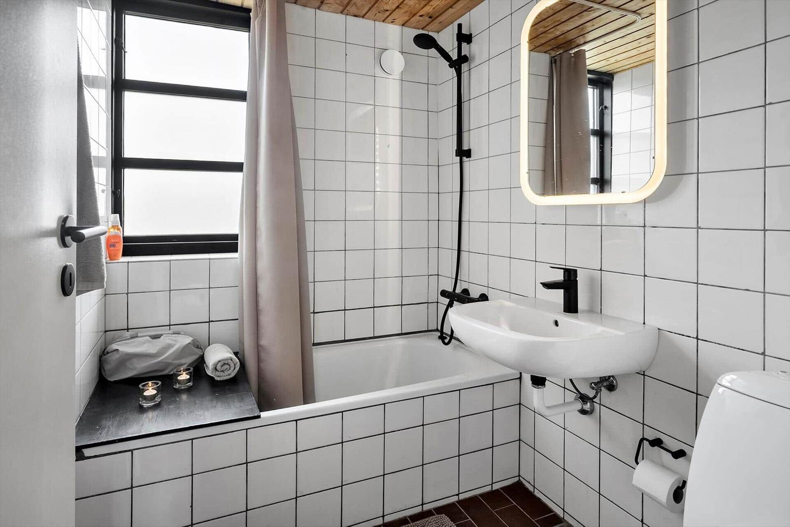 Badezimmer mit Badewanne, Duschkopf, Waschbecken und Spiegel.