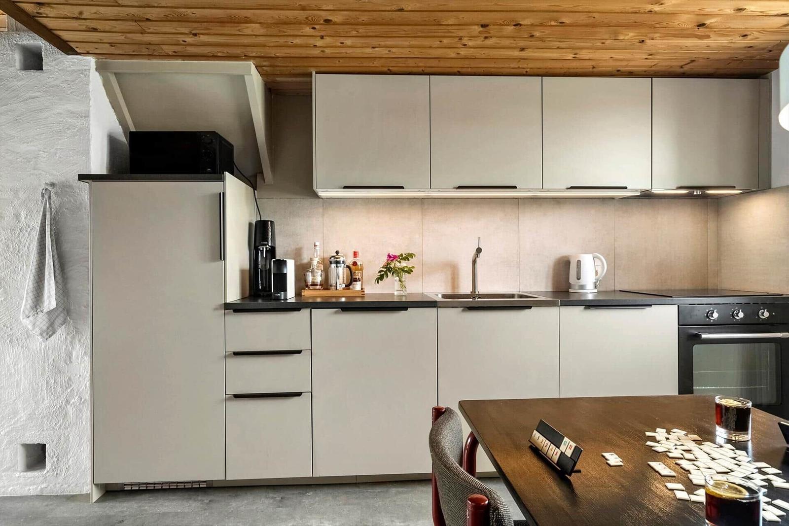 Küche mit Holzdecke, grauen Schränken und Essbereich mit Tisch und Stühlen.