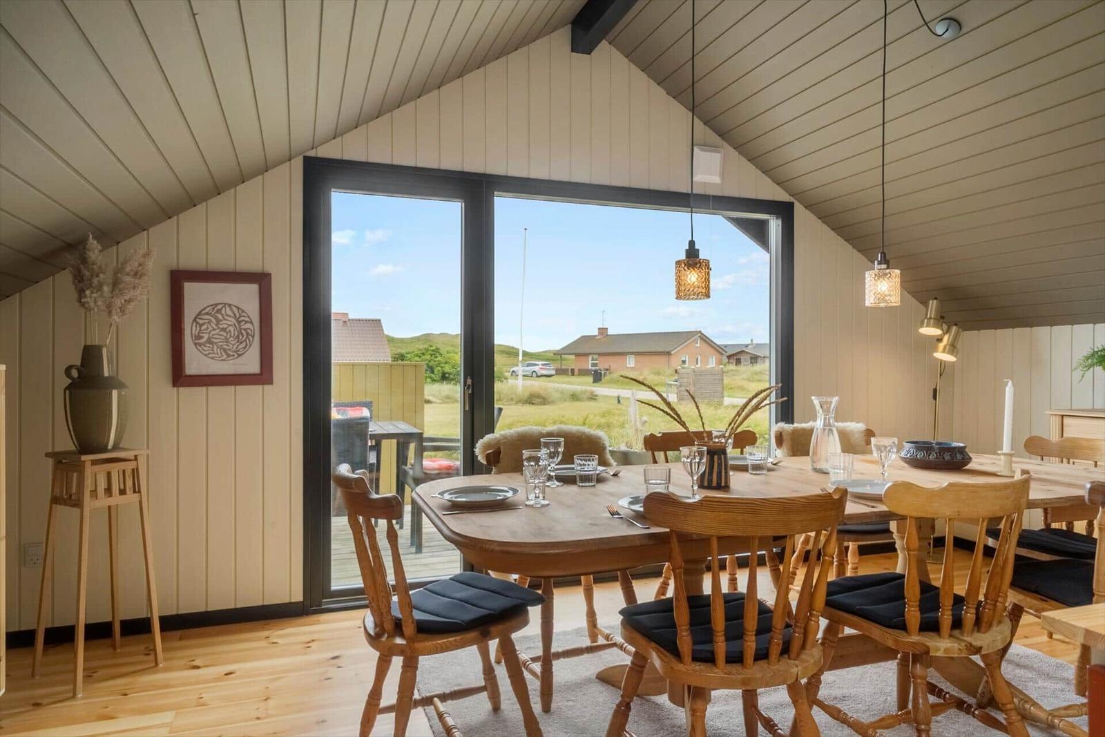 Esszimmer mit Holztisch, Stühlen und Blick auf die Landschaft.