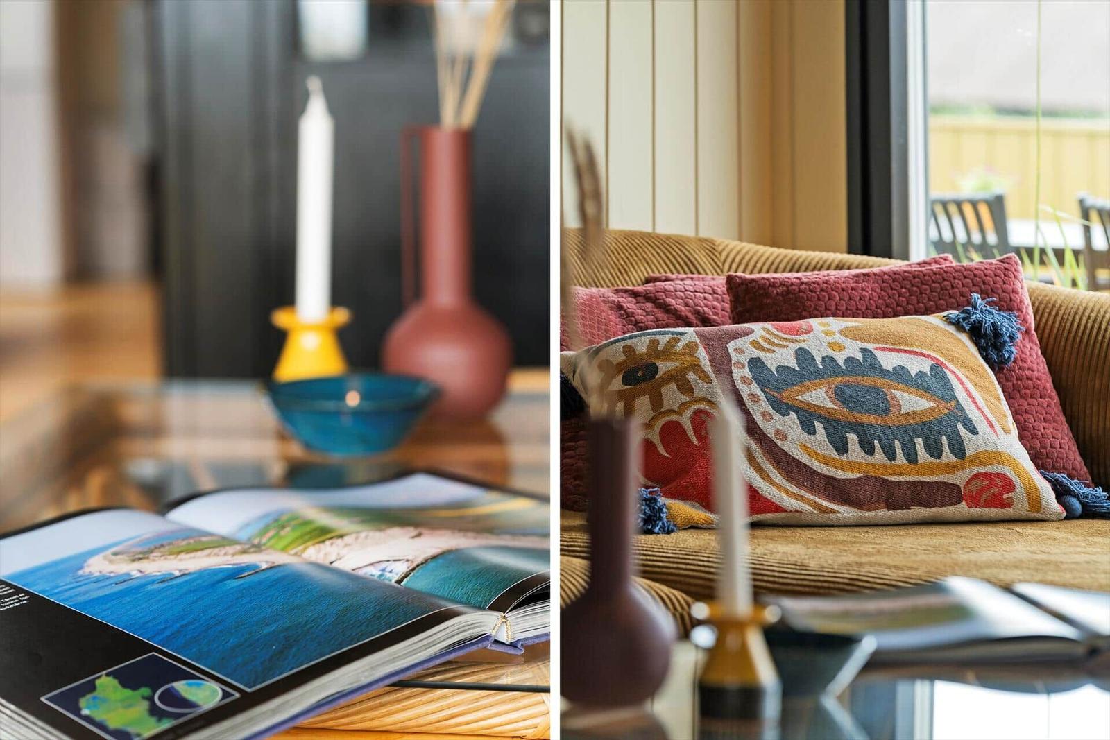 Ein Wohnbereich mit Sofa, Kissen und Tisch mit Kerzen und Buch.