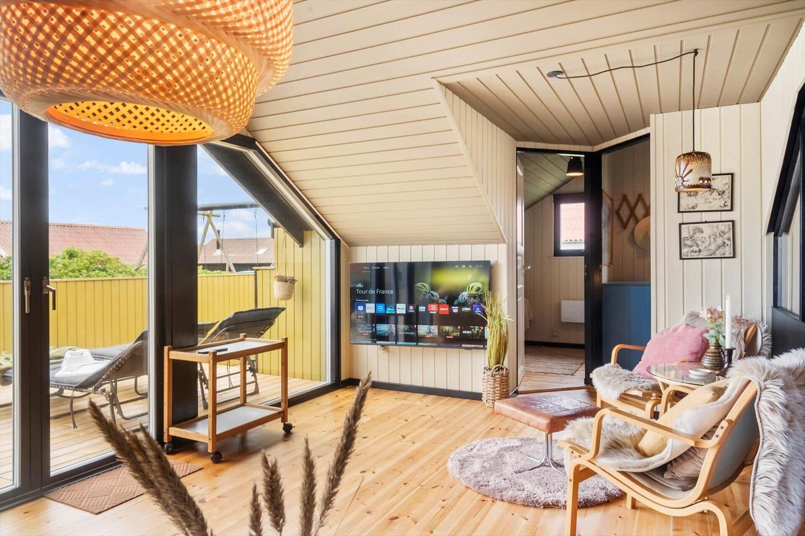 Wohnbereich mit TV, Sitzgelegenheiten und Blick auf die Terrasse.