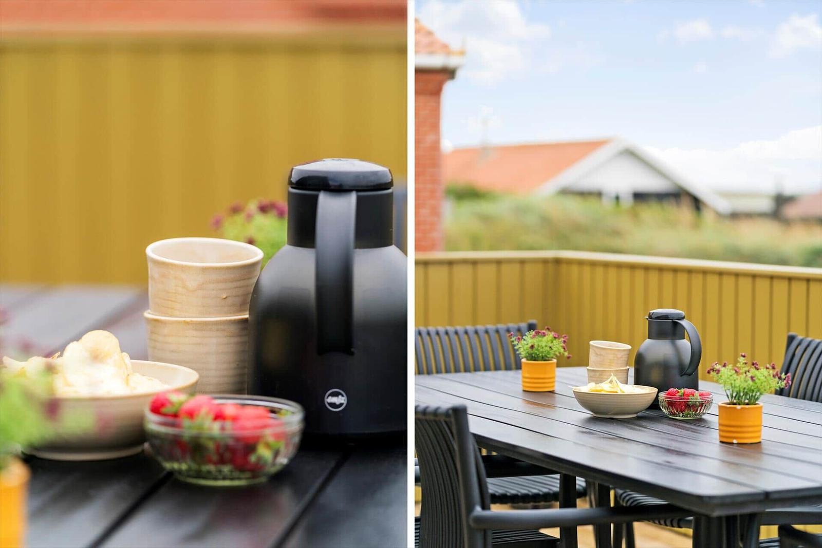 Terrasse mit Tisch, Stühlen, Obst und Thermoflasche.