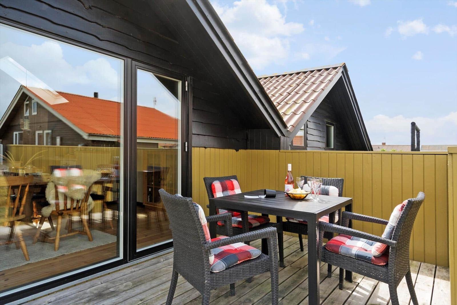 Terrasse mit Tisch und Stühlen, Blick auf benachbarte Häuser.