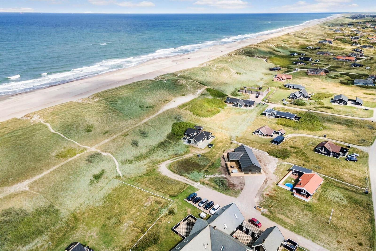 Aerial view of beachfront properties with dunes and ocean.