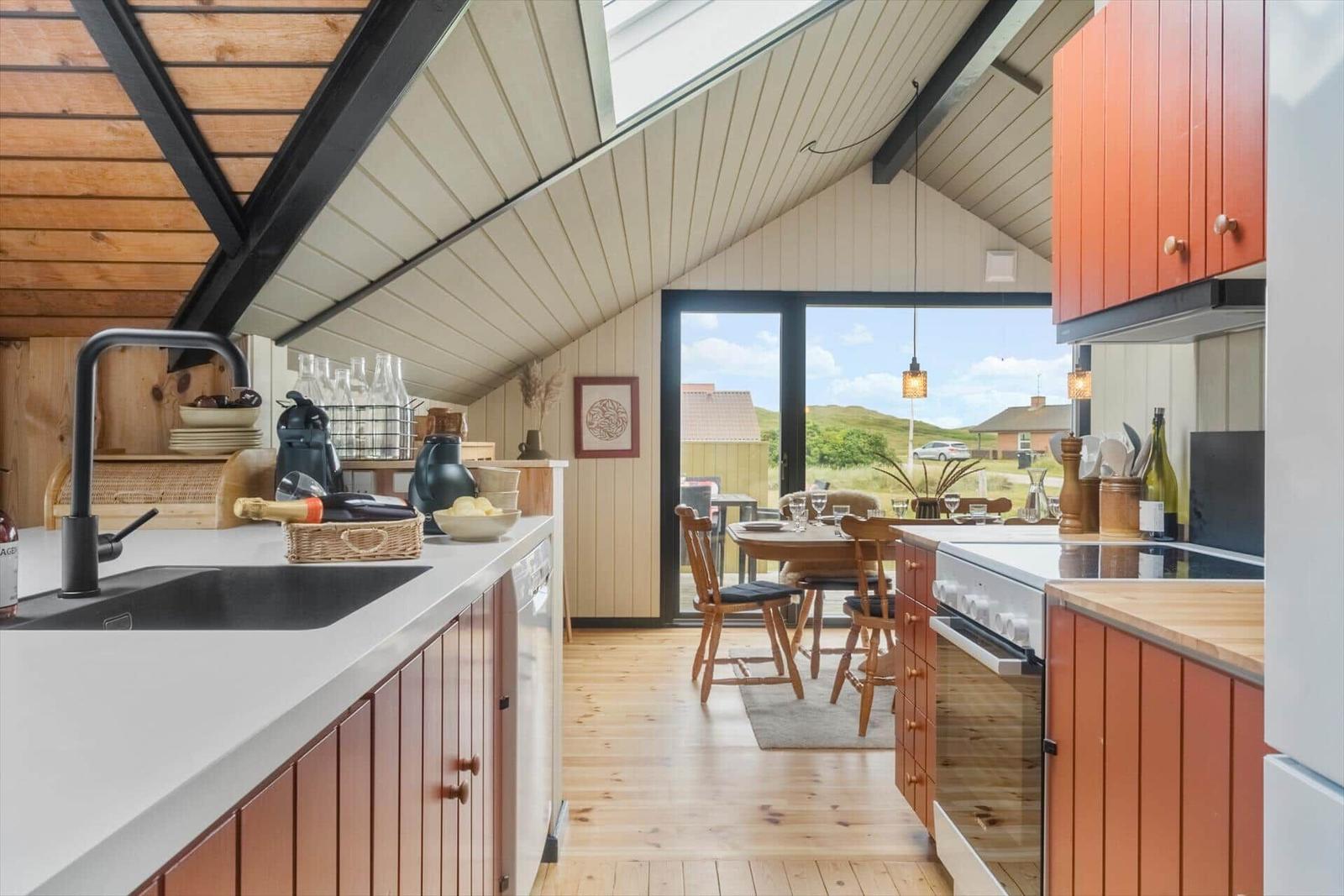 Küche mit Essbereich, Holzboden und großem Fenster mit Blick auf die Landschaft.