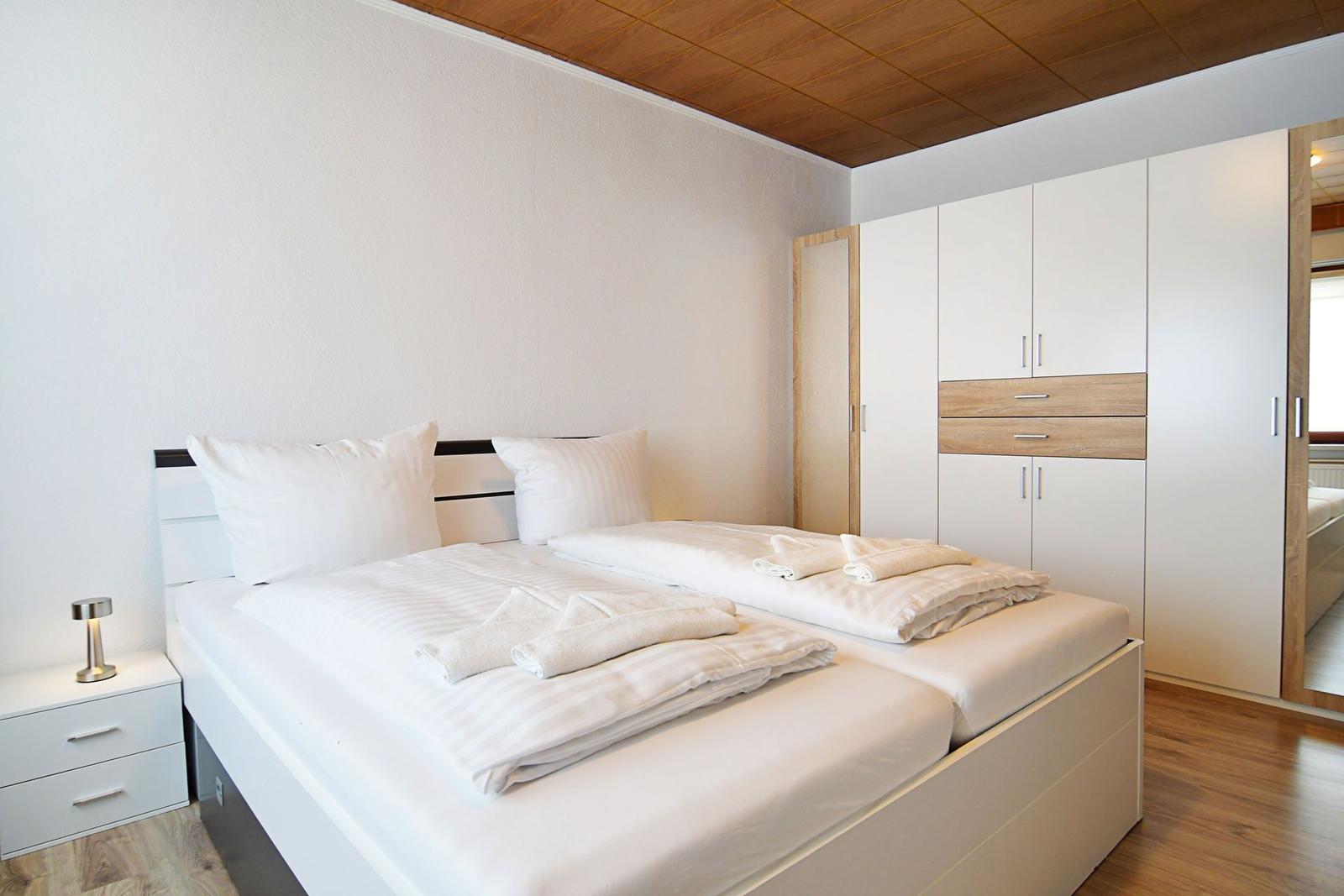 Schlafzimmer mit Doppelbett, Kleiderschrank und Nachttisch.