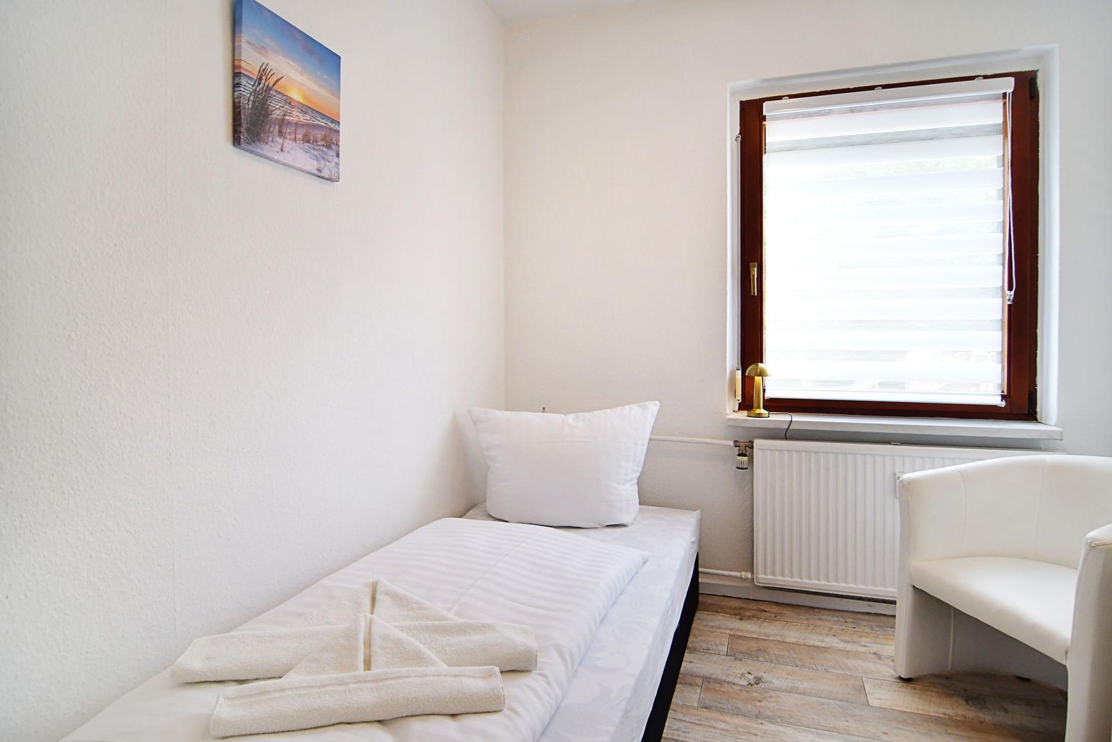 Ein Schlafzimmer mit Bett, Fenster und Sitzgelegenheit.