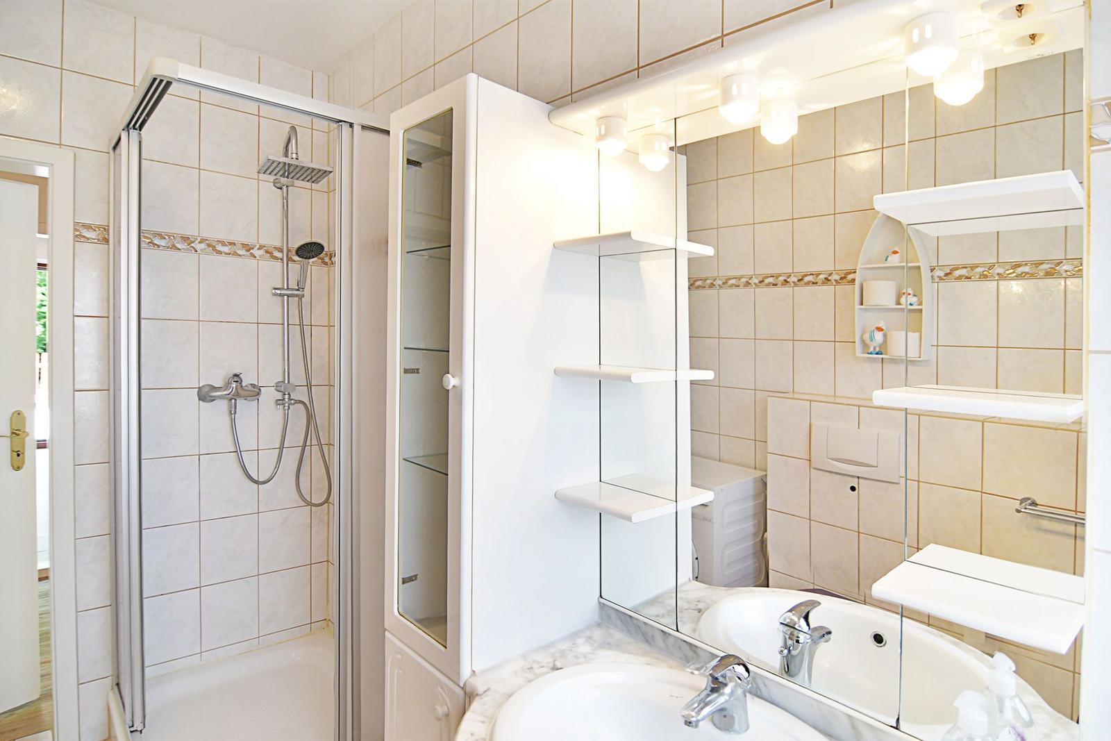 Badezimmer mit Dusche, Waschbecken und Spiegelschrank.