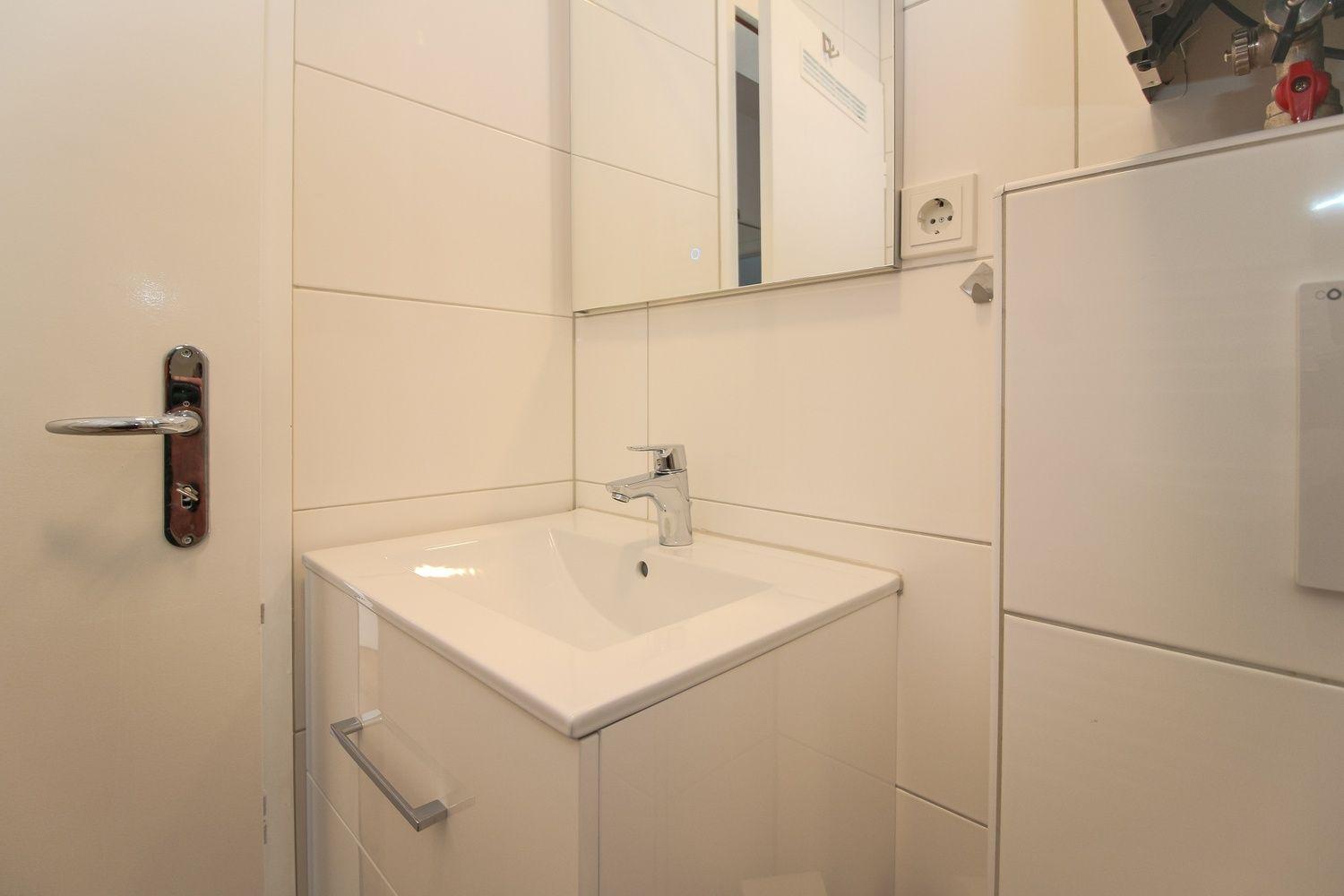 Badezimmer mit Waschbecken, Spiegel und Tür