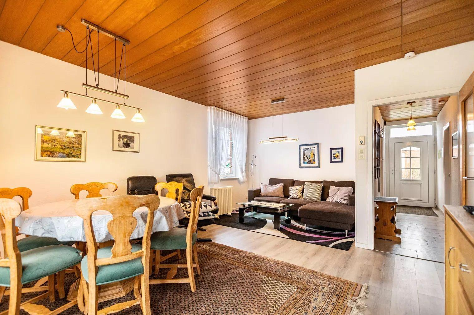 Wohn- und Essbereich mit Holzdecke, Sofa, Esstisch und Stühlen.