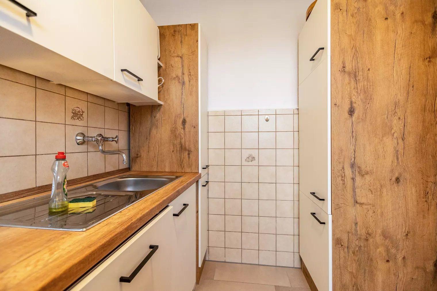 Küche mit Holzoberfläche, Spüle und weißen Schränken