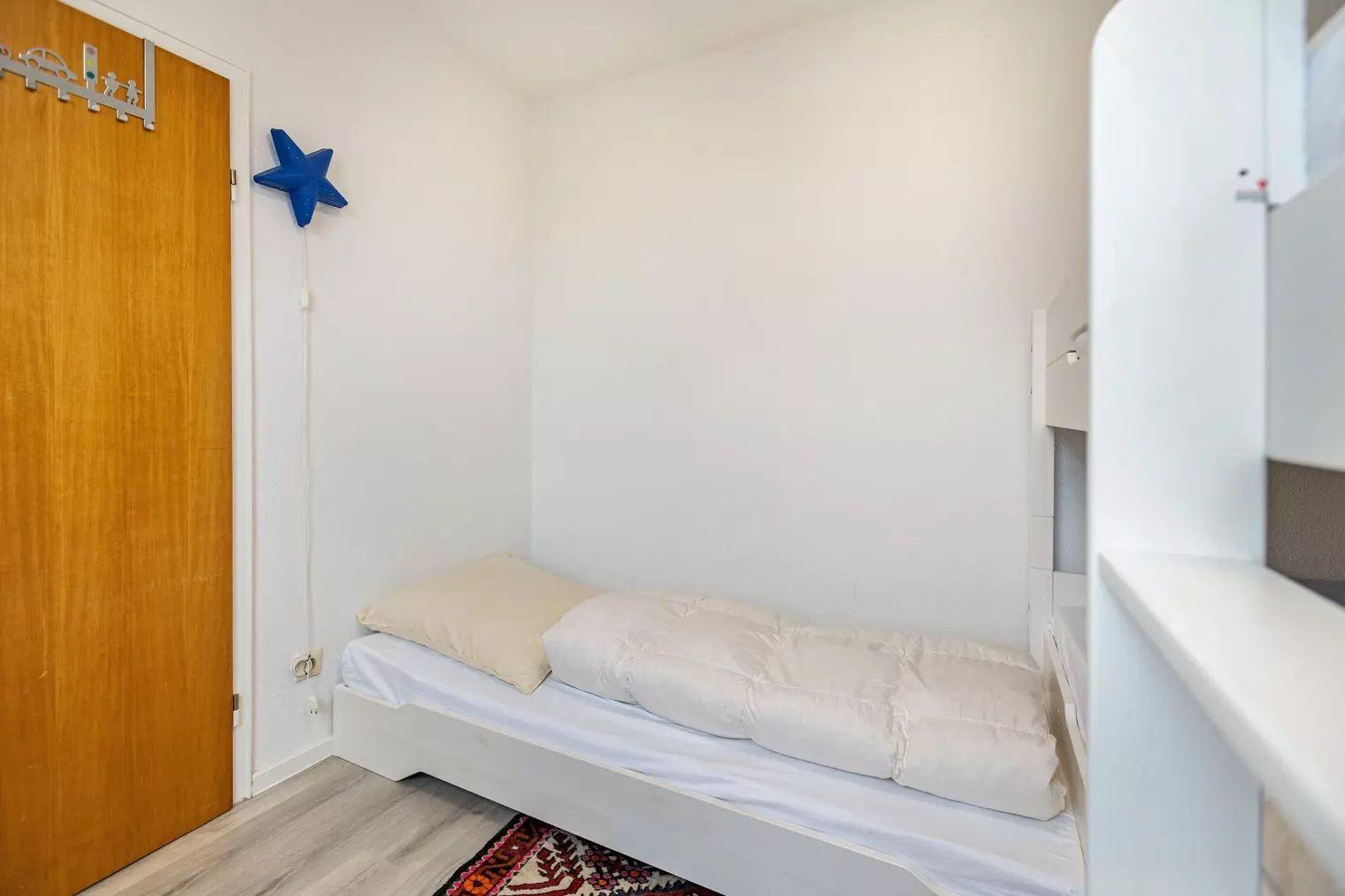 Ein Schlafzimmer mit einem Bett, einer Tür und einer blauen Stern-Dekoration an der Wand.