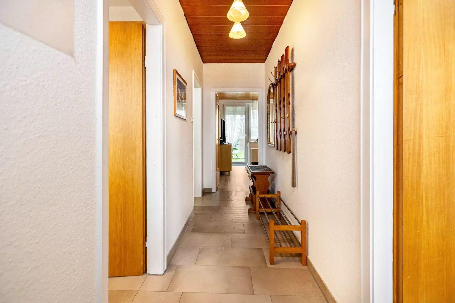Flur mit Holzdecke, Schuhschrank und Skiaufhängern an der Wand.