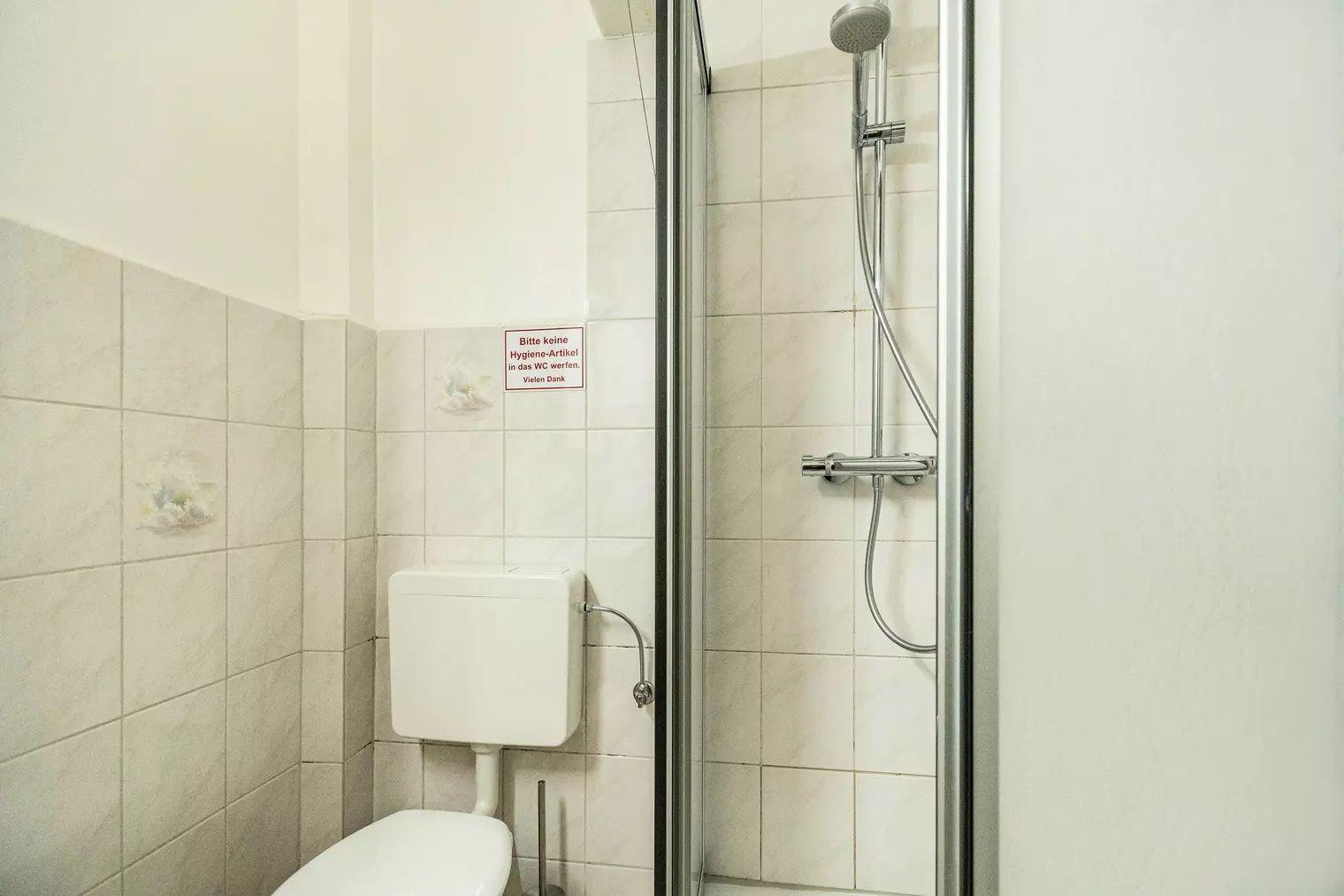 Badezimmer mit Dusche, WC und Wandbezeichnung.