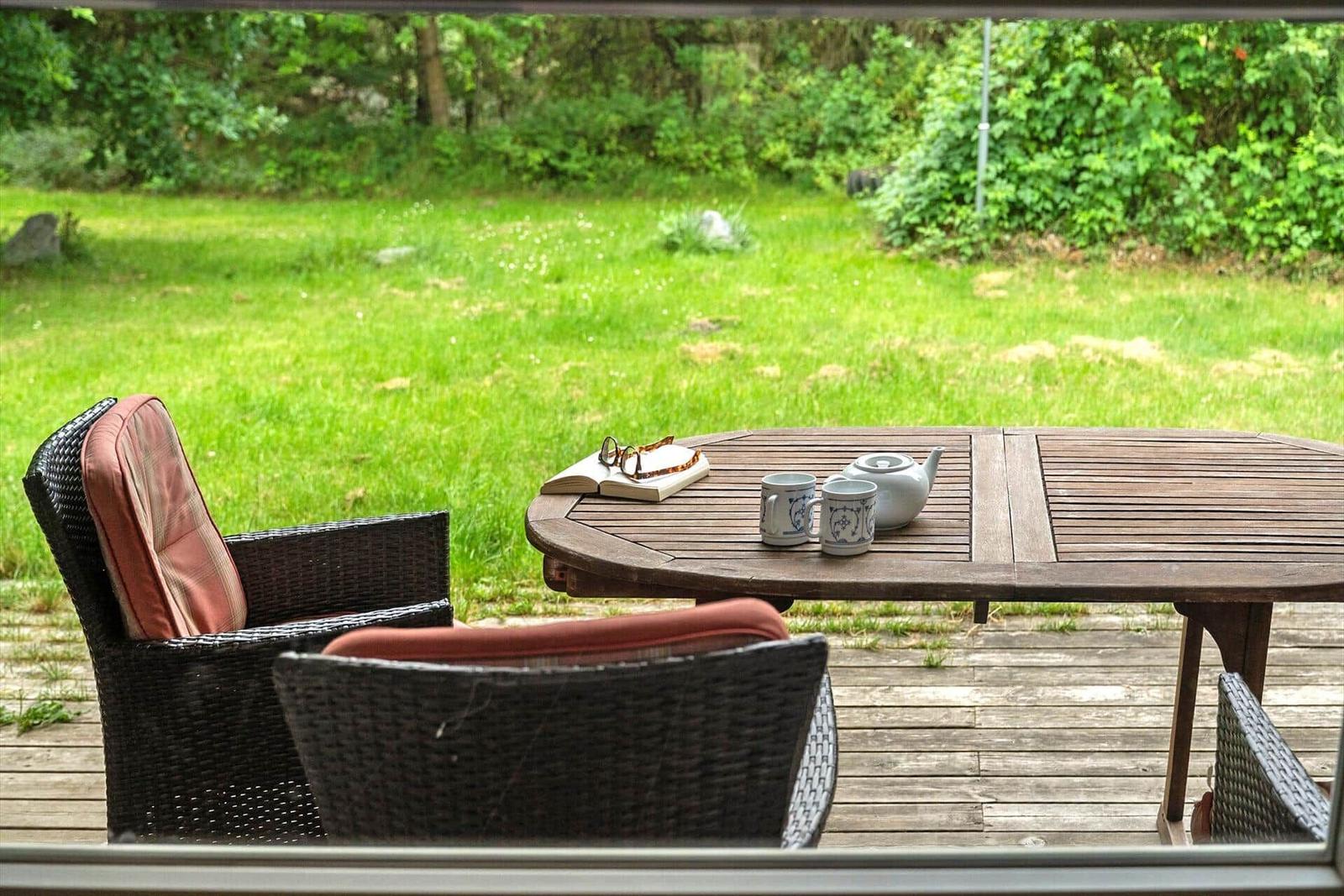 Terrasse mit Tisch, Stühlen und Blick auf grünen Rasen