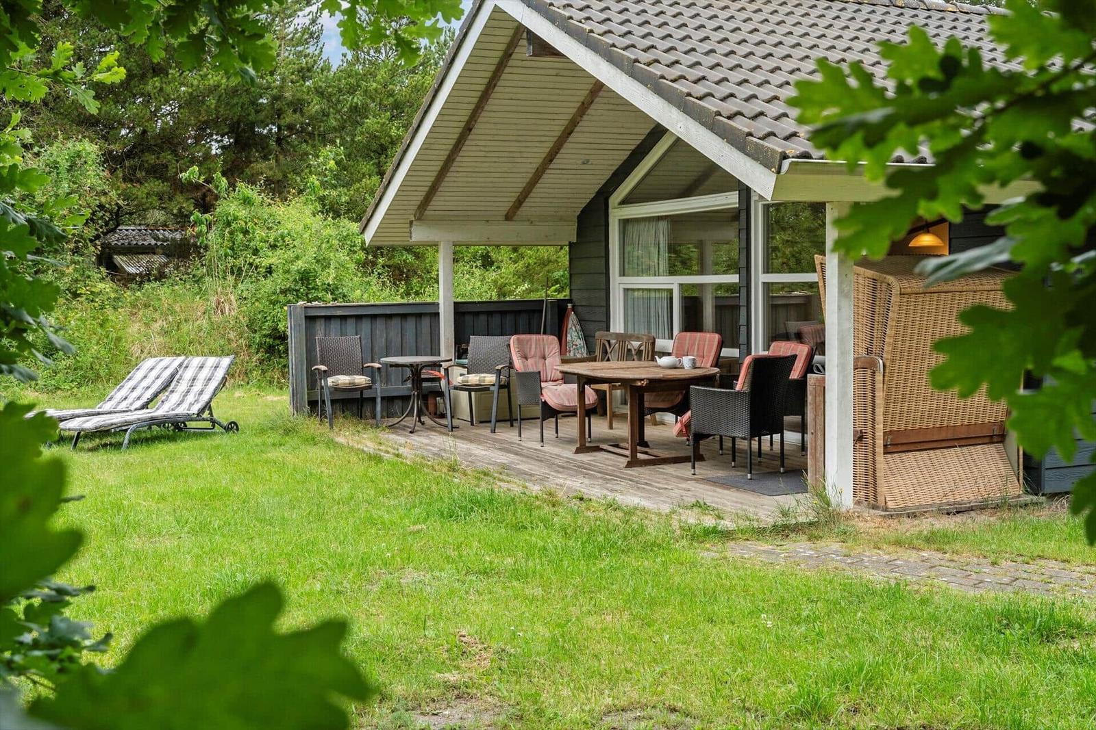 Terrasse mit Tisch, Stühlen und Liegestühlen im Garten.