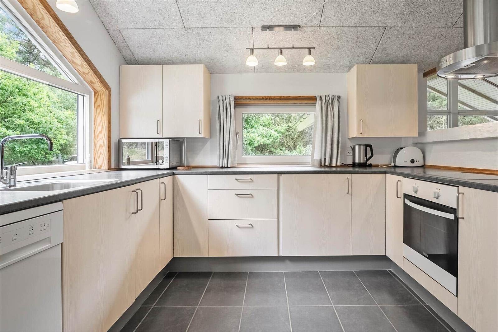 Küche mit hellen Schränken, Fenstern und moderner Ausstattung.