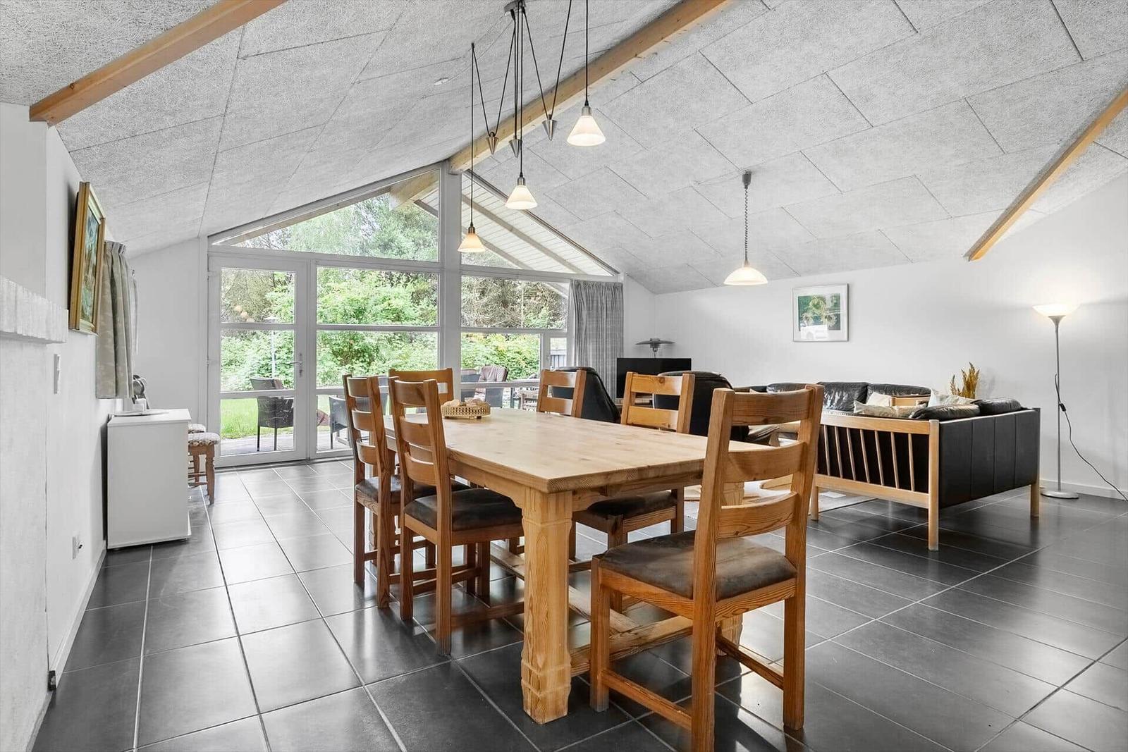 Großer Raum mit Esstisch, Sofa und Glasfront zum Garten