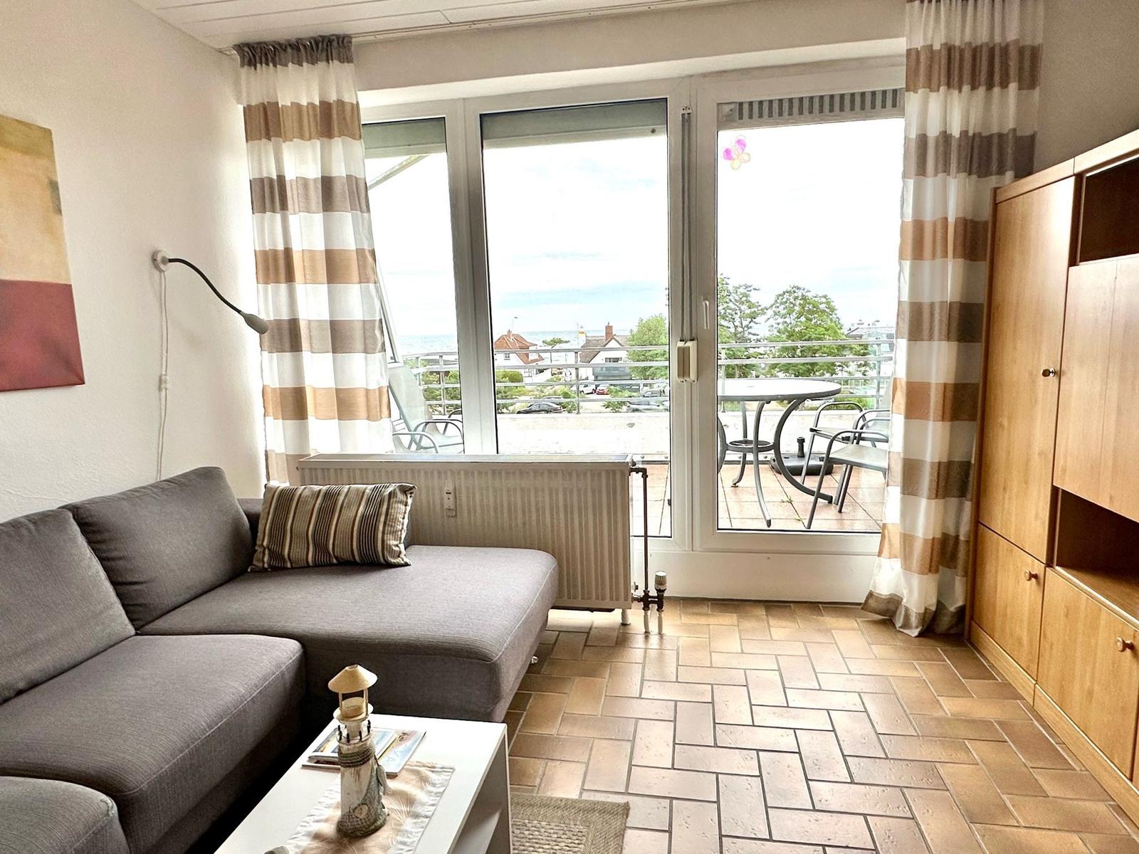 Wohnzimmer mit Sofa, Balkon und Blick aufs Meer.
