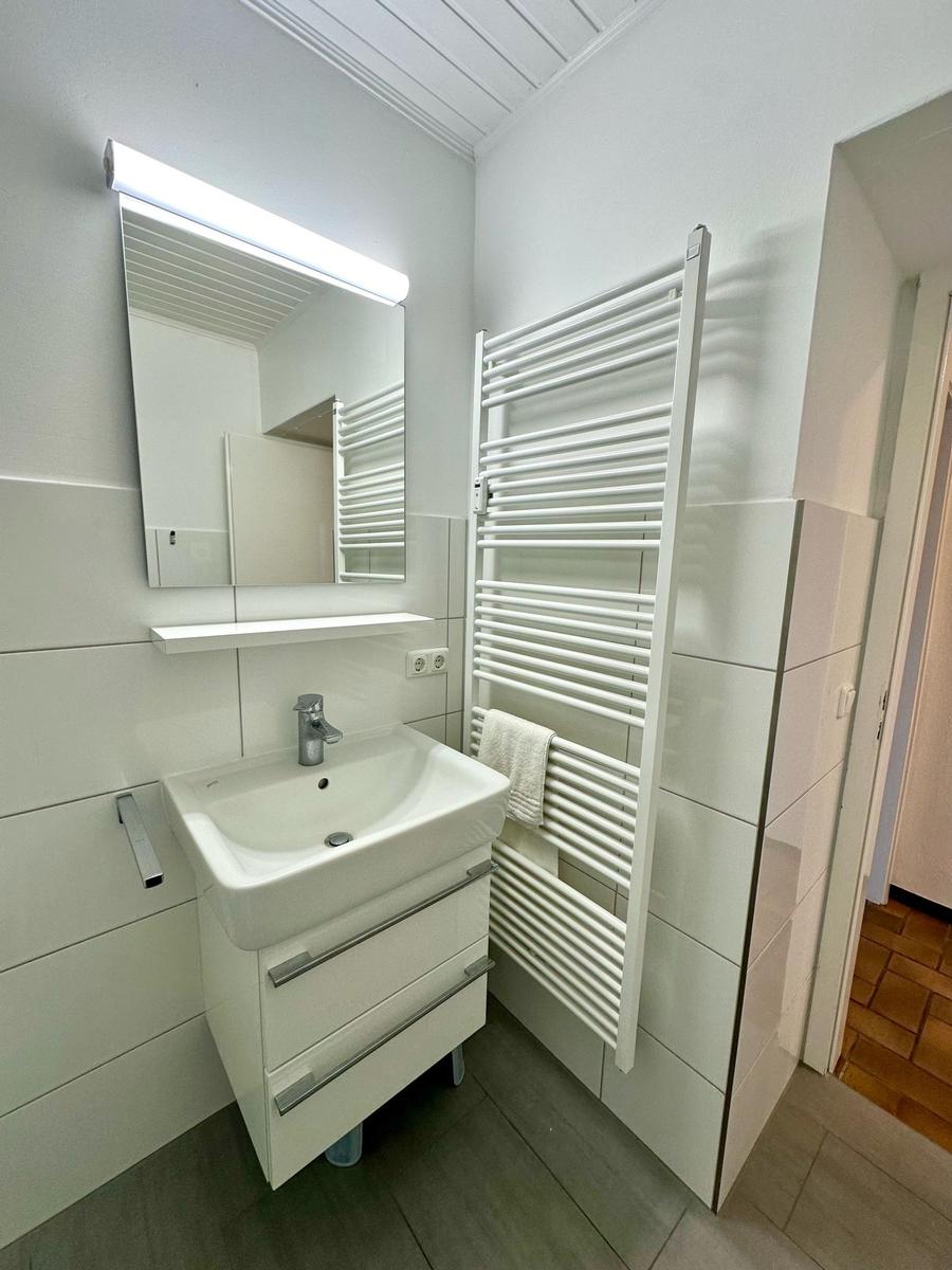 Badezimmer mit Waschbecken, Spiegel und Heizkörper