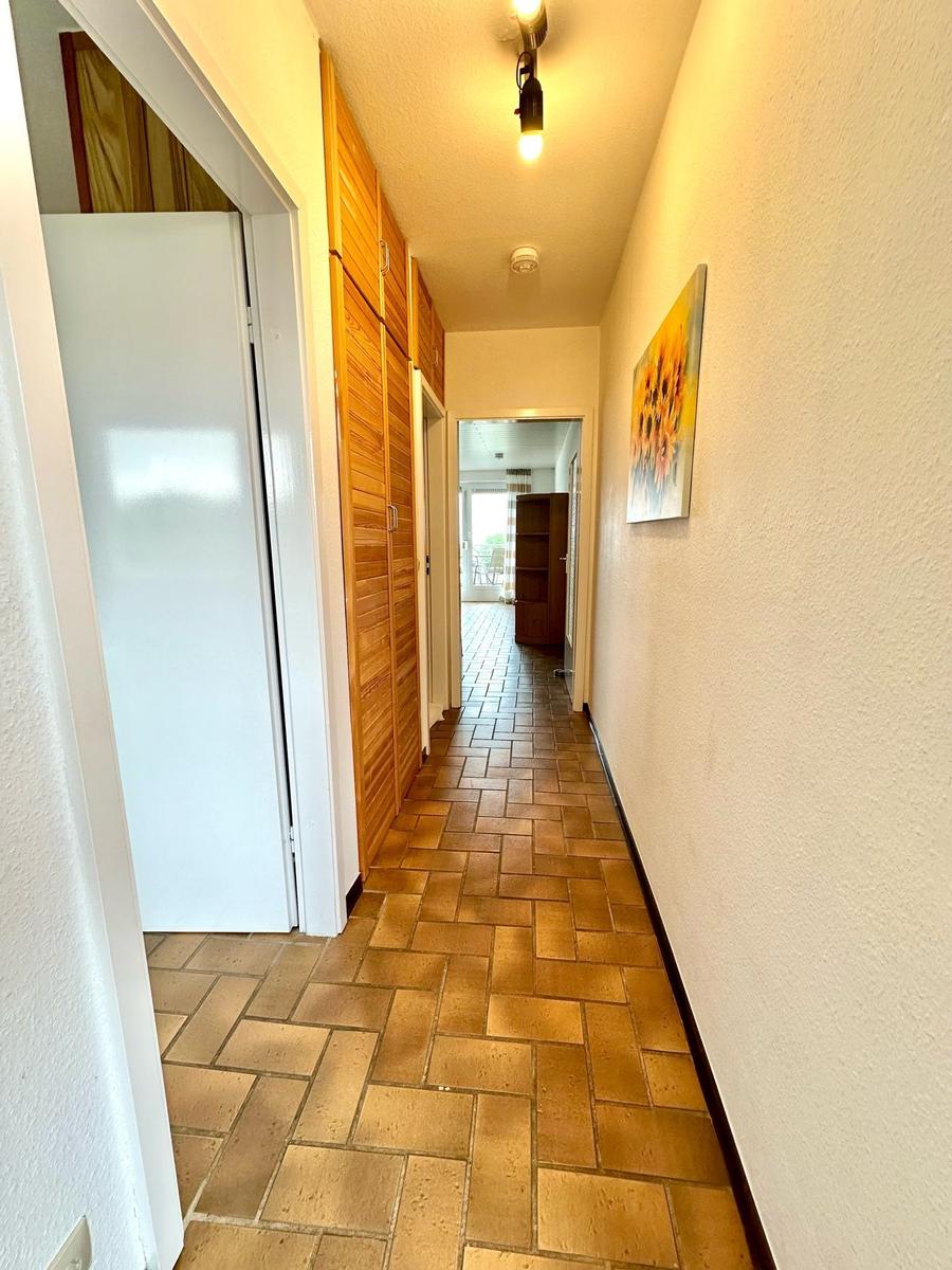 Flur mit Holzschrank, Kachelboden und Wandbild