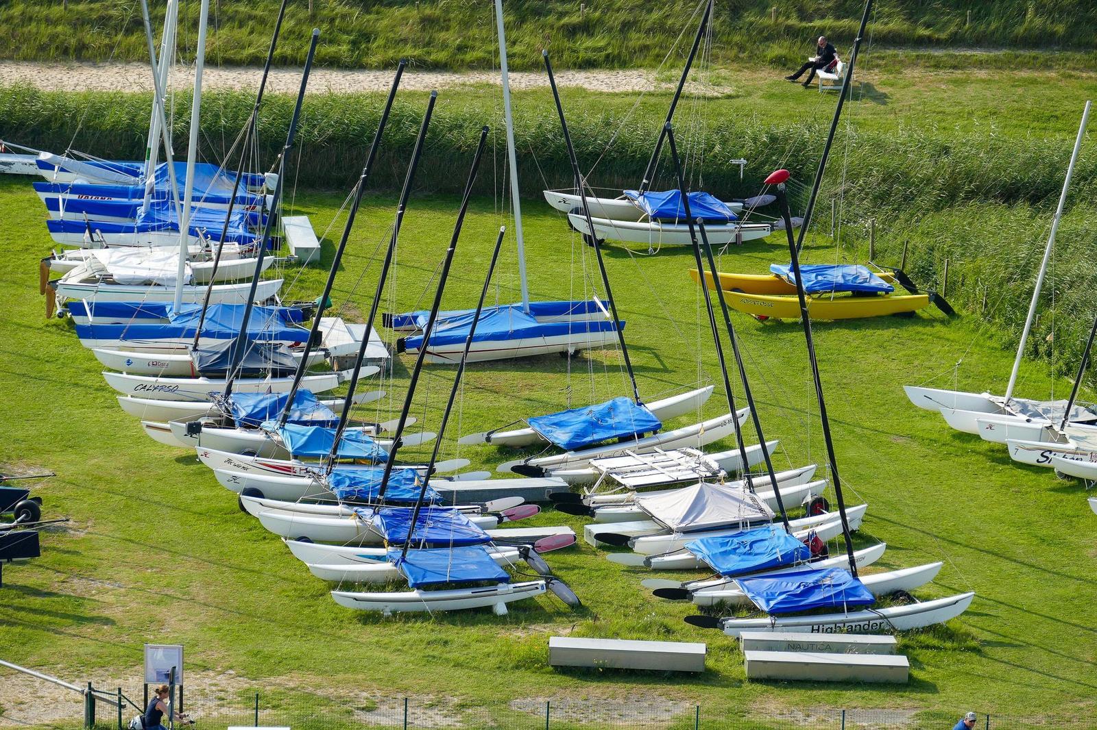 Mehrere Segelboote mit blauen Plane auf grünem Rasen.