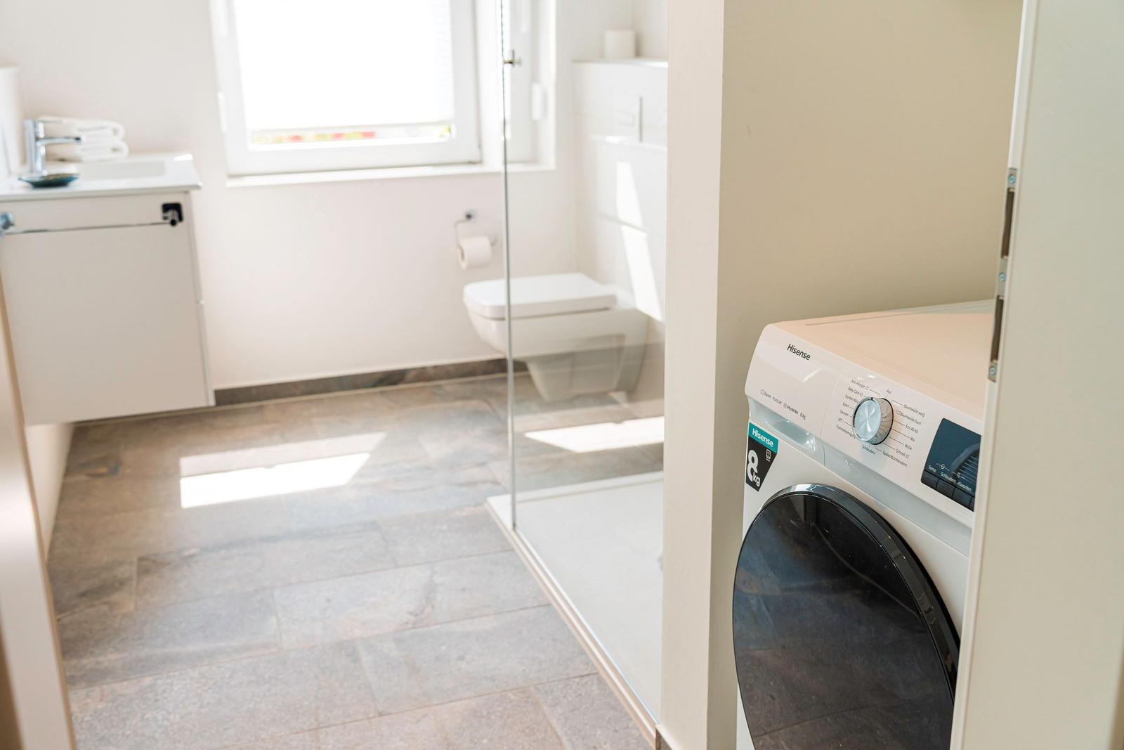 Badezimmer mit Waschmaschine, Toilette und Waschbecken.
