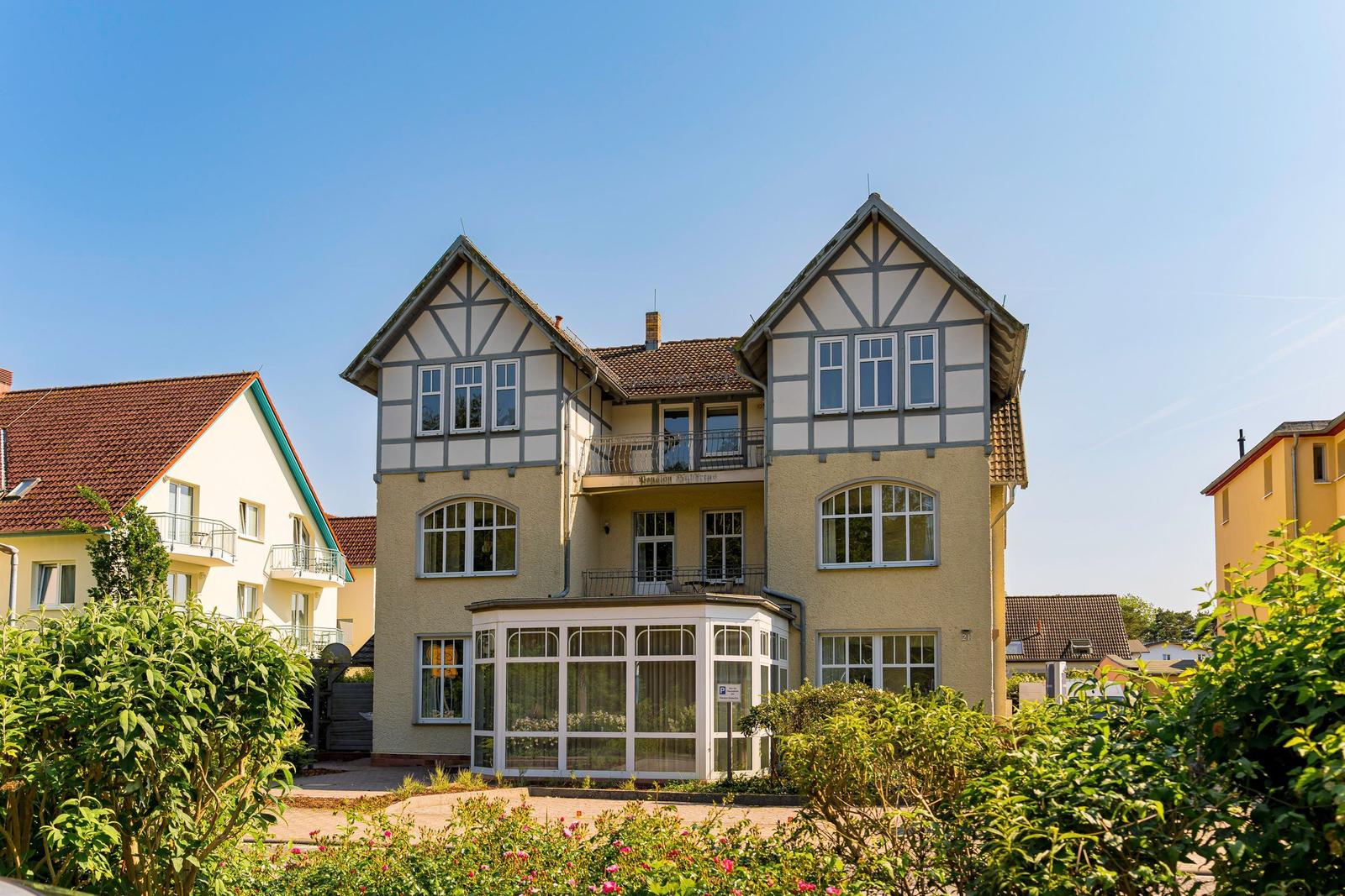 Zweistöckiges Haus mit Balkon und Wintergarten im Grünen.