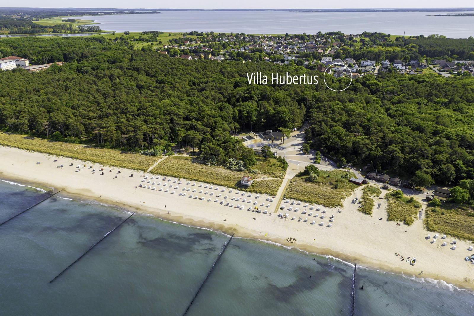 Villa Hubertus liegt am Strand mit Wald und See im Hintergrund.