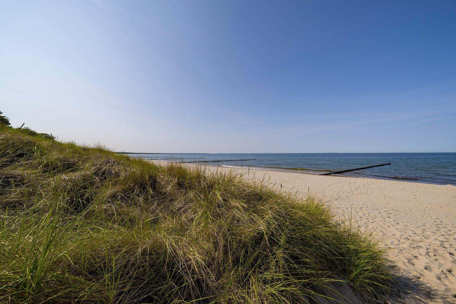 Strand mit Sanddünen und Meer unter blauem Himmel