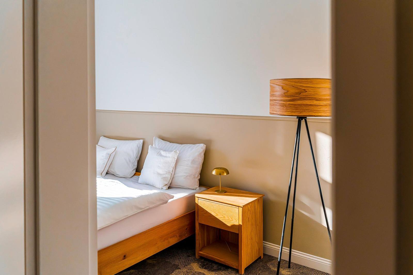 Schlafzimmer mit Bett, Nachttisch und Stehlampe.