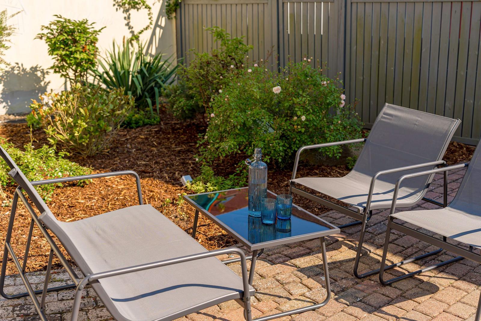 Terrasse mit drei Liegestühlen und Tisch mit blauen Gläsern.
