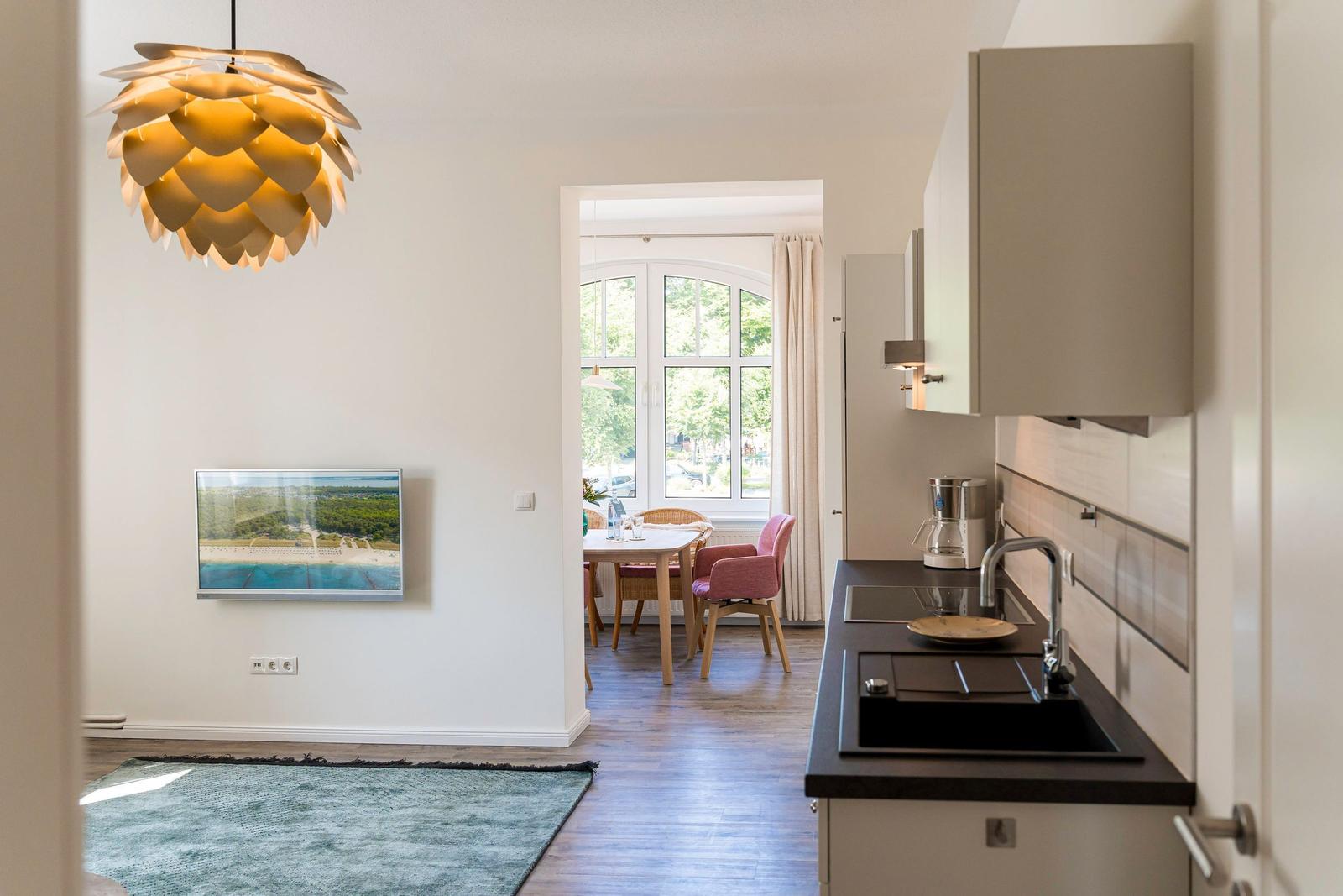 Küche mit Essbereich und Wohnzimmer mit Wandbild und Pendelleuchte.