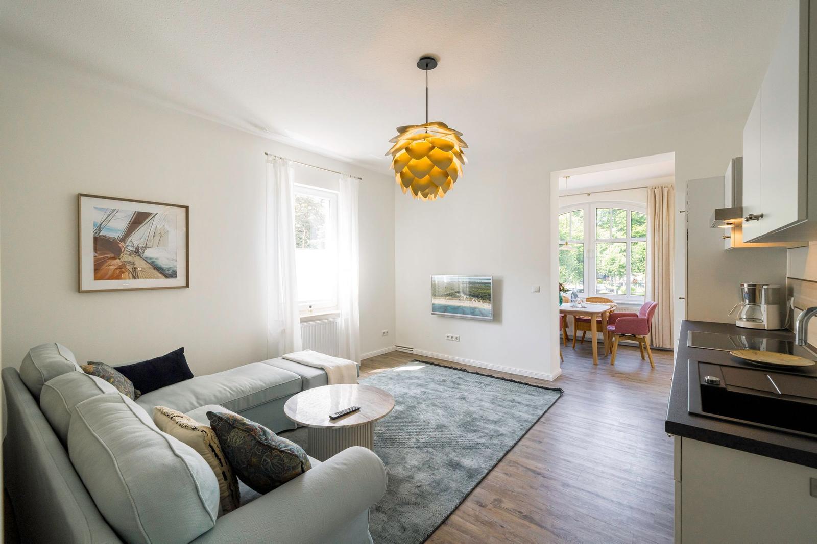 Wohn- und Essbereich mit Sofa, Tisch und Küchenzeile.