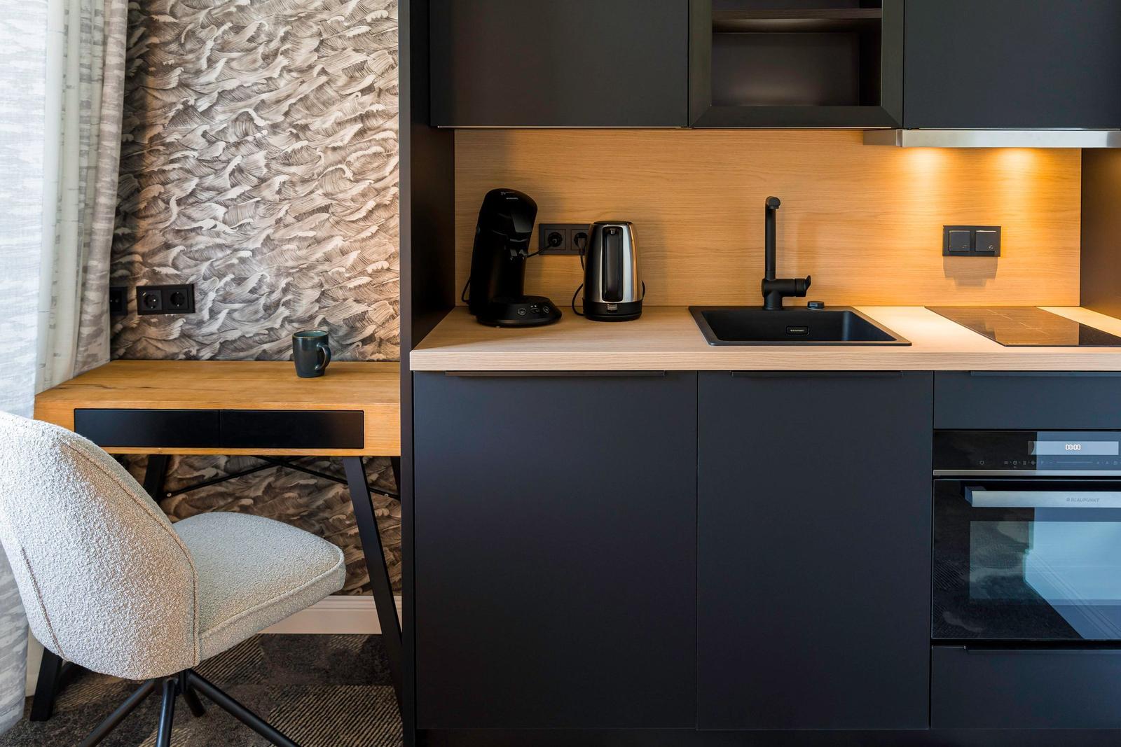 Küche mit Arbeitsfläche, Spüle, Kaffeemaschine und Kühlschrank.