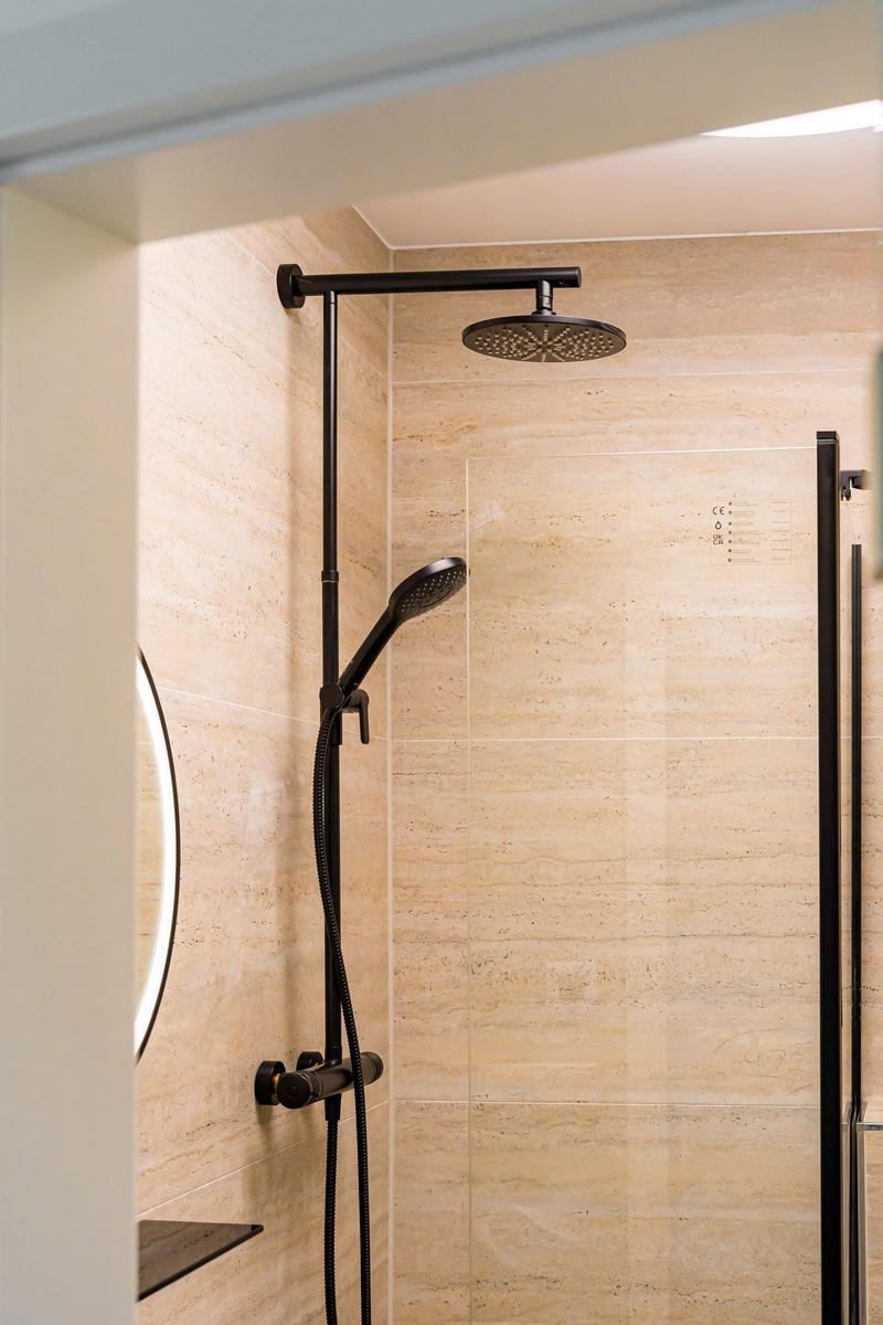 Duschkabine mit schwarzer Dusche und Steinwand