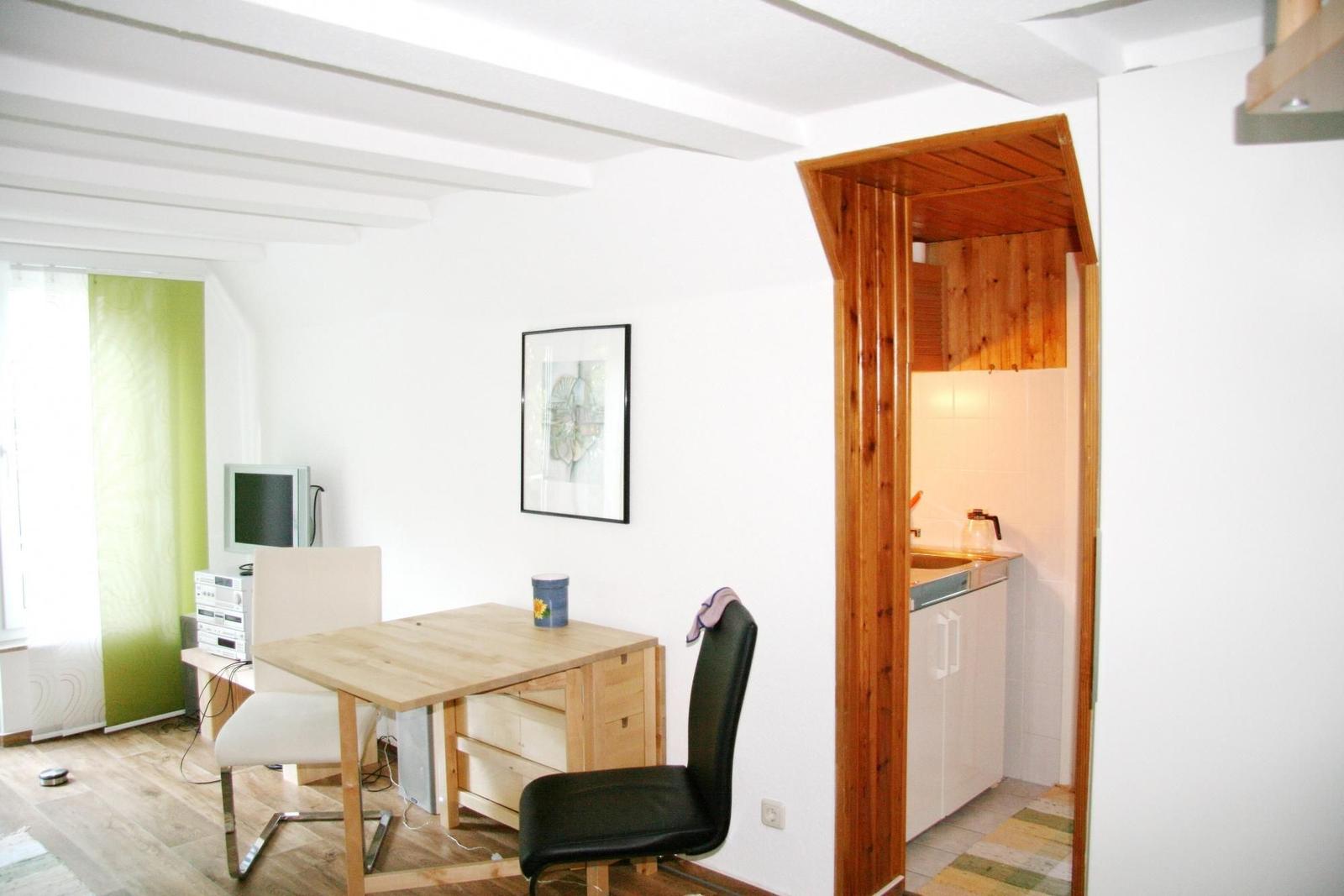 Wohn- und Küchenbereich mit Holztisch, Stühlen und Fenster