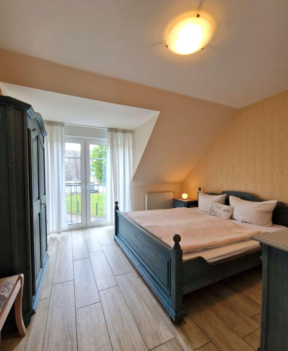 Schlafzimmer mit Balkon, Bett, Kleiderschrank und Holzboden.