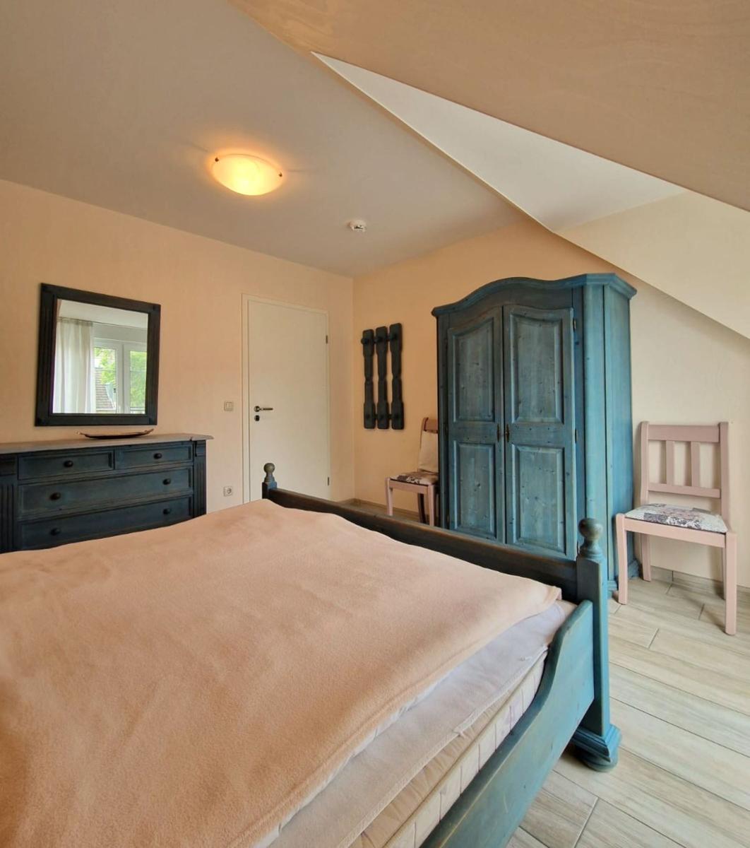 Schlafzimmer mit Bett, Kleiderschrank und Stuhl unter schrägem Dach.