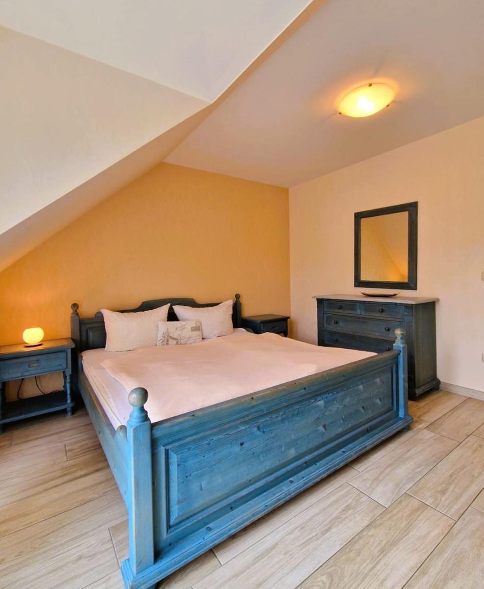 Schlafzimmer mit Bett, Nachttisch und Schrank unter schrägem Dach.