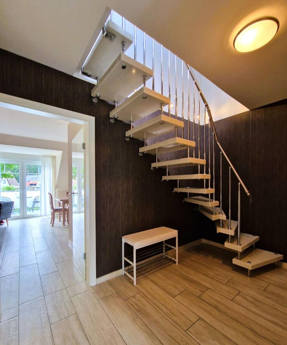 Moderne Treppe mit Holzstufen und Metallgeländer führt nach oben.