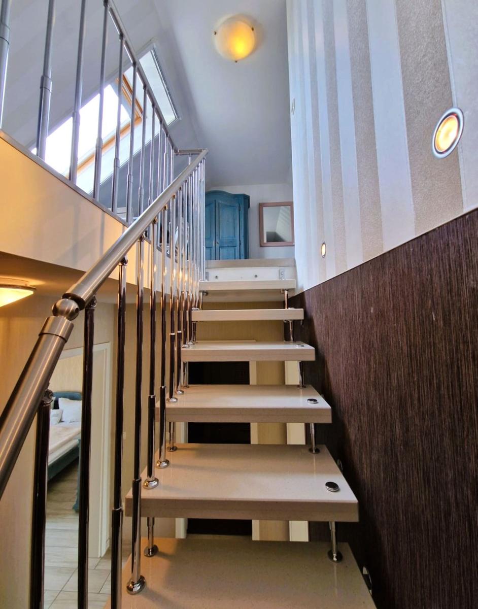 Moderne Treppe mit Metallgeländer führt zu einer oberen Etage.