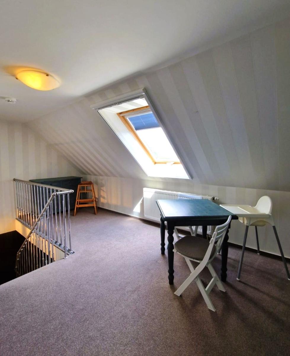 Dachgeschosszimmer mit Tisch, Stühlen und Dachfenster.