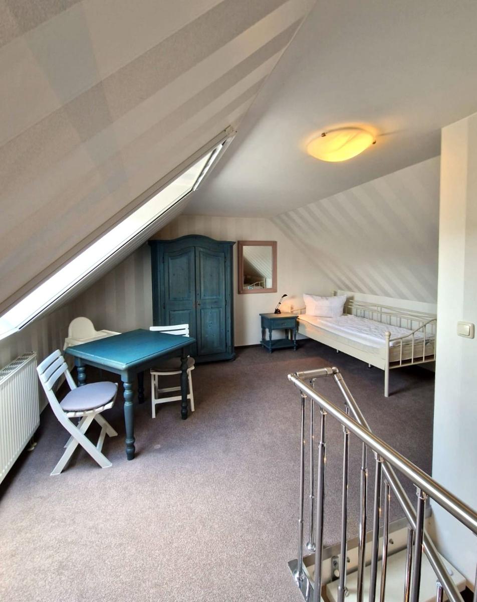 Dachgeschosszimmer mit Bett, Tisch, Stühlen und Schrank unter Dachschräge.