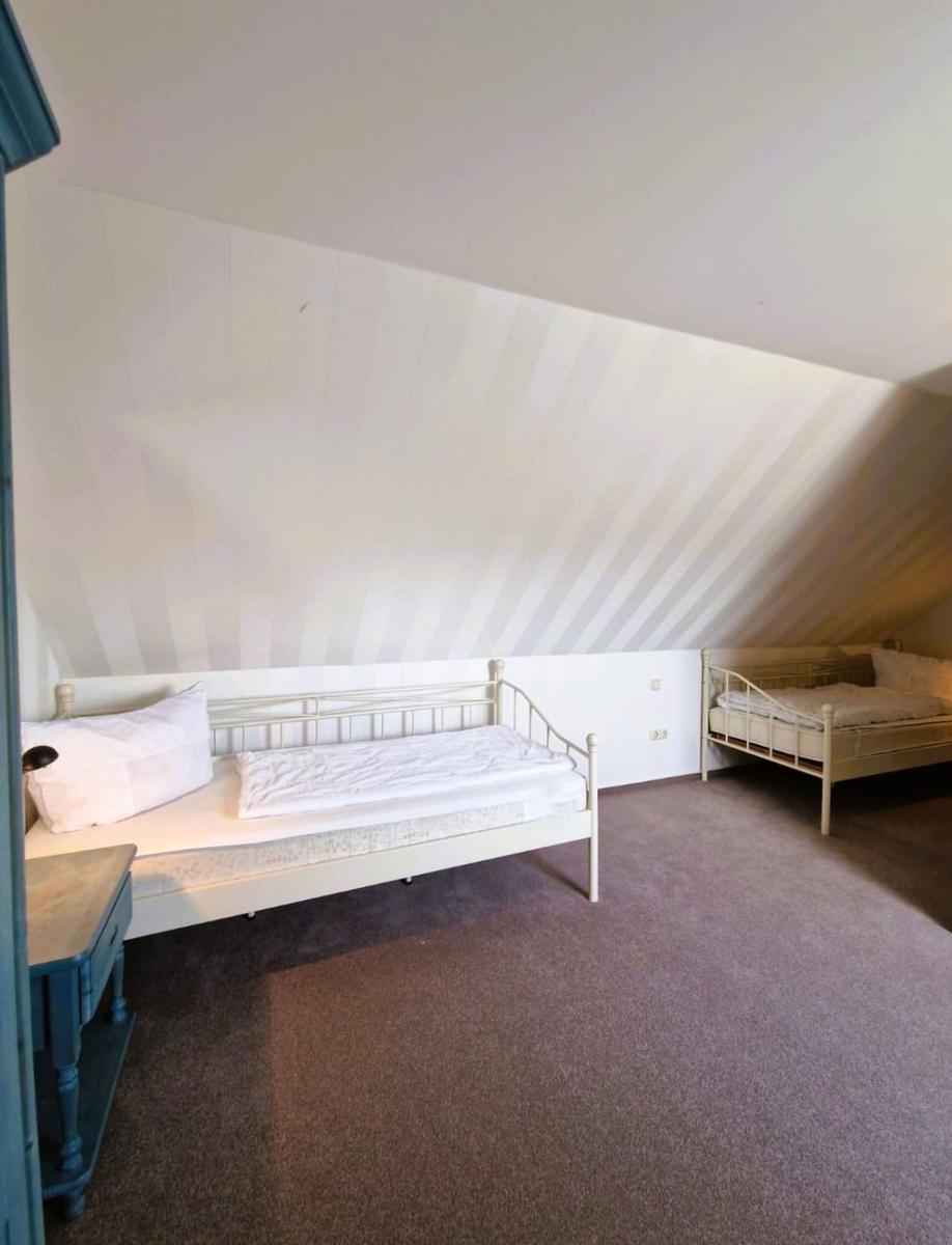 Zimmer mit zwei Betten unter schrägen Dachdecken und Teppichboden.