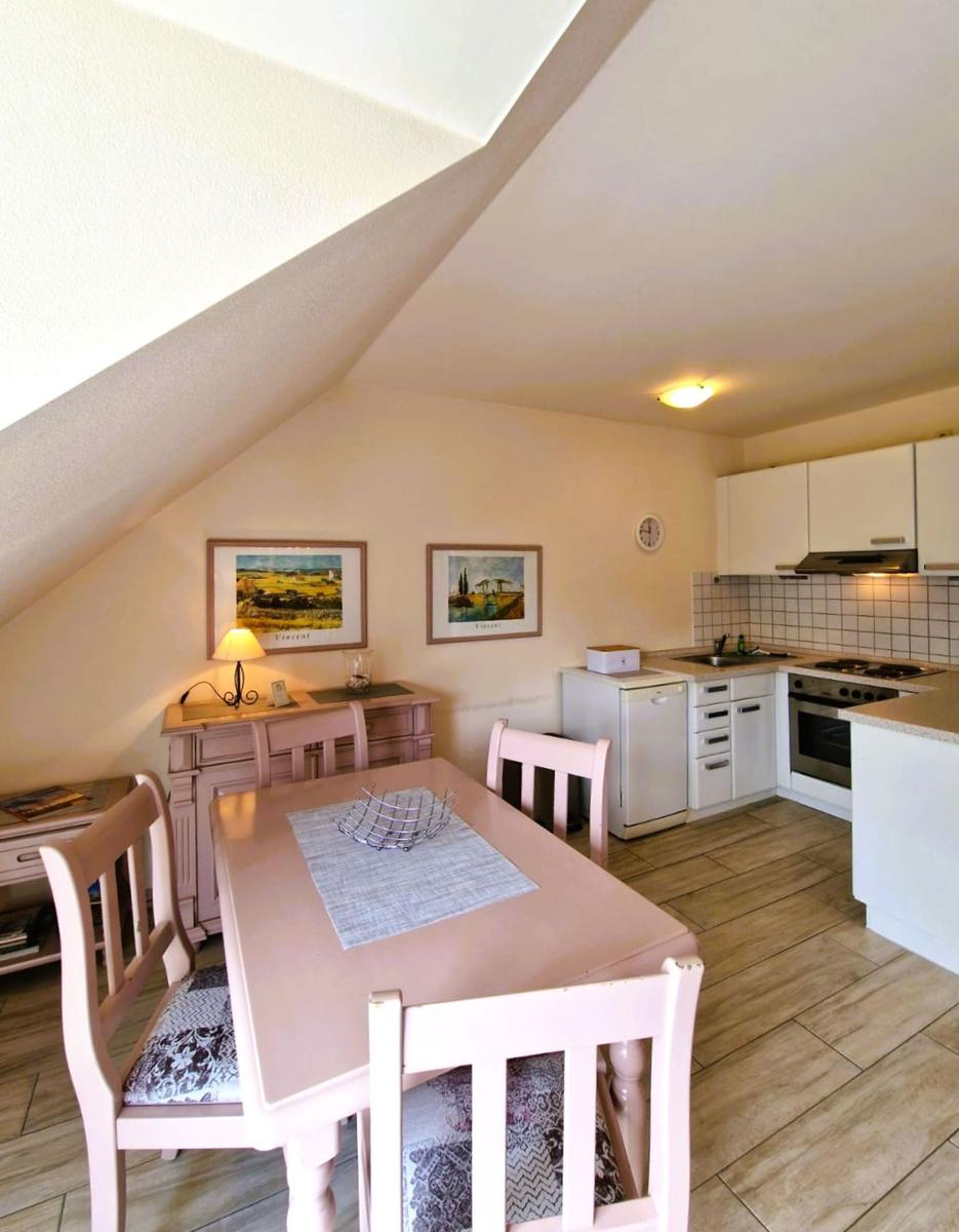 Essbereich mit Tisch und Stühlen, Küche mit weißen Schränken und Kacheln an der Wand.