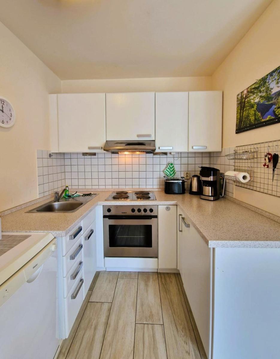 Küche mit weißen Schränken, Edelstahlherd und Holzdielenboden.